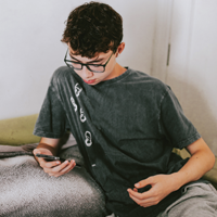 一名拉丁裔青少年在电话会议上盯着手机屏幕的照片